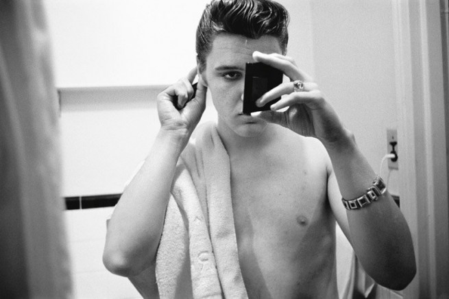 С помощта на джобно огледалце, Елвис дооправя косата си в банята на своя апартамент в хотел Уоруик, Ню Йорк Сити. 1956г.